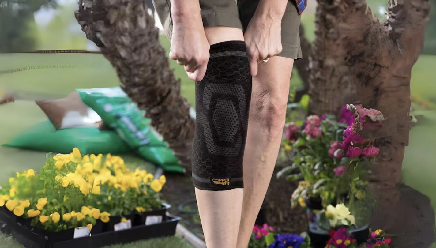 Person outdoors putting on a Copper Fit compression sleeve on their leg for support